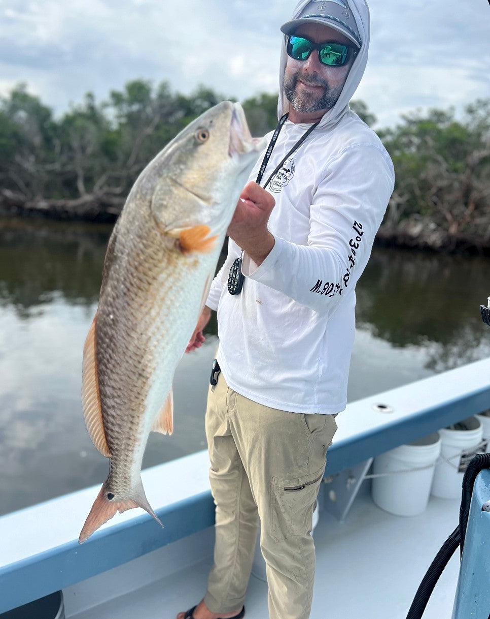 Capt. Justin Moore, who throws the Dropout Chain Gang chain-bottom cast net, holding a redfish on his boat